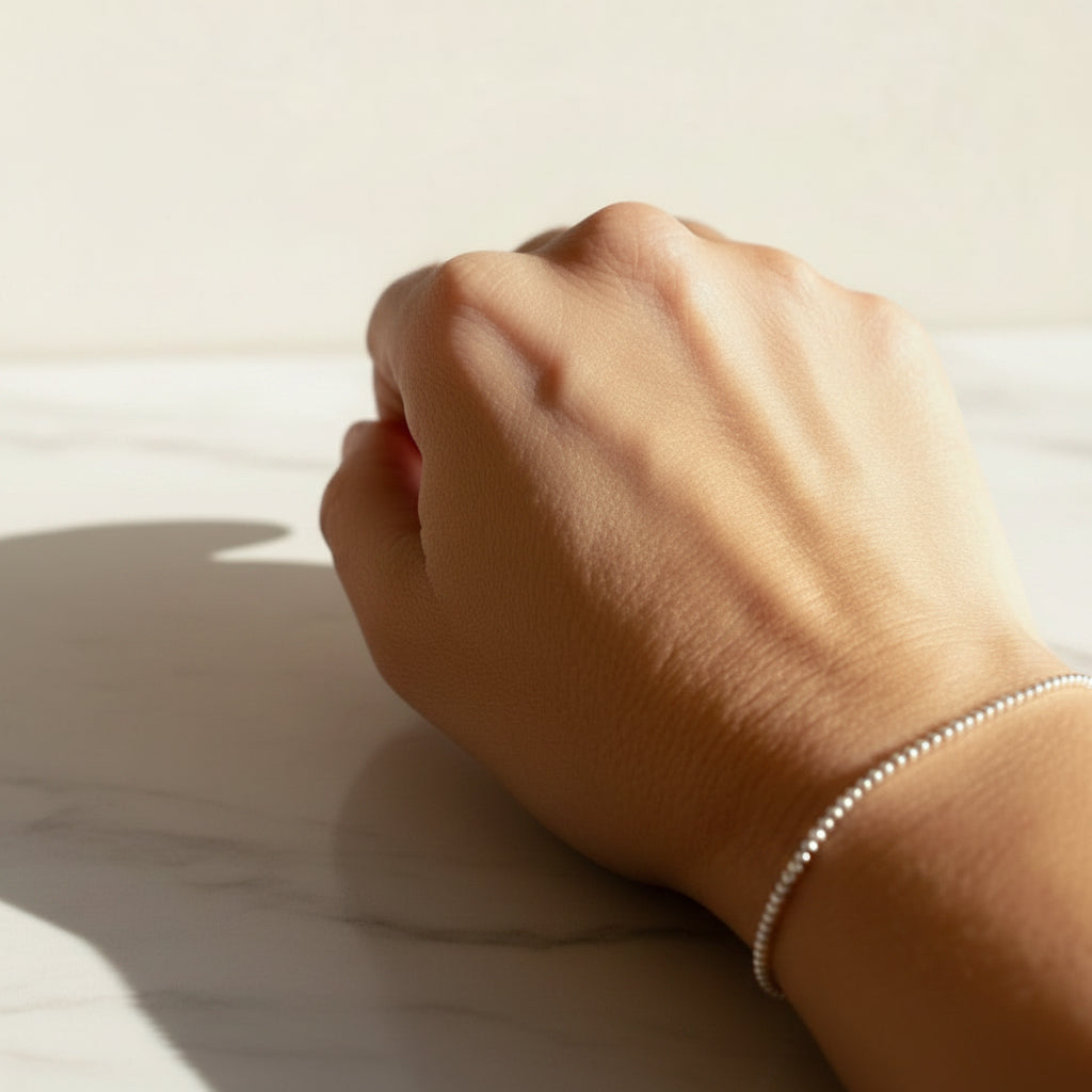 A silver bracelet with mini spheres design, military style,displayed on a person's wrist.